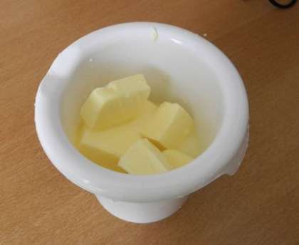 В глубокую миску разрезать масло и добавить сгущенное молоко