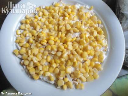 Баночку кукурузы слить на сито. Положить на лук 1/2 банки зерна кукурузы и посыпать зерна граната.