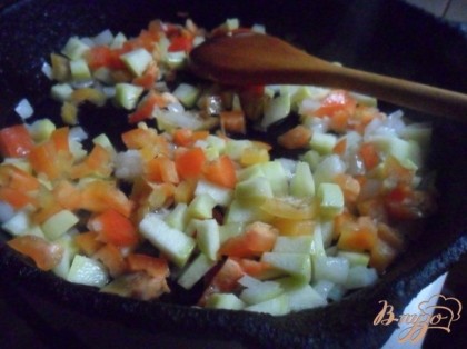 В сковороде разогреть растительное масло и обжарить лук, кабачок и перец 5 минут.