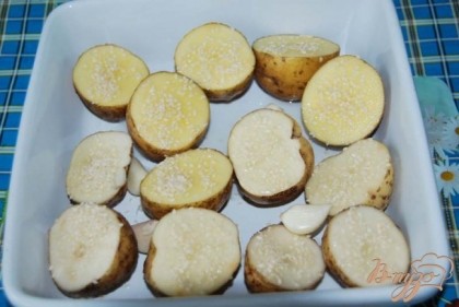 Укладываем картофель в форму для запекания, слегка сбрызгиваем растительным маслом, солим, между картофелинами укладываем зубчики чищенного чеснока и каждую картофелину посыпаем подсушенным кунжутом. Ставим в нагретую до 200 градусов духовку на 1 час.