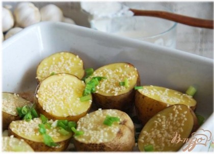 Готовый картофель посыпаем мелкопорезанным зелёным луком. Подаем картофель со сметанным соусом. Запечённый чеснок можно также растолочь и для вкуса добавить в соус.