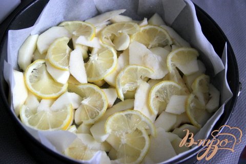 Форму застелить пекарской бумагой, смазать маслом. Очищаем и нарезаем ломтиками яблоки, также нарезаем лимон. Укладываем их на бумагу