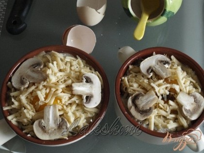 Посыпать натёртым сыром и выложить сверху пластинки грибов для украшения.Запечь в разогретой духовке при 180 градусах около 15 минут до расплавления сыра.