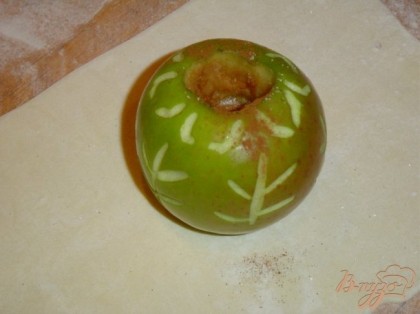 Берем яблоко и удаляем сердцевну. Раскатываем тесто и вырезаем квадрат.На него ставим яблоко,предвартельно заполнив выемку сахаром и корицей.