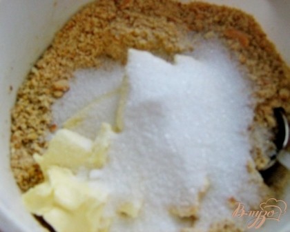 Грецкие орехи измельчить в блендере. Смешать крошки печенья, орехи, сахар и масло в однородную массу.
