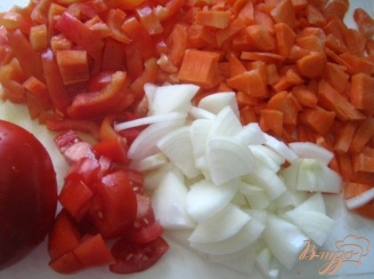 Тем временем готовим овощи для соуса. Нарезаем кубиками 1 луковицу, морковь, болгарский сладкий перец, чеснок, помидоры.