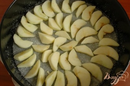 Форму для выпекания застелить пергаментной бумагой, смазать маслом и присыпать сахаром.Выложить ломтики очищенных яблок. Сбрызнуть соком лимона.