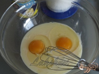 В миску выливаем банку сгущёнки, добавляем 2 яйца и хорошо перемешиваем.