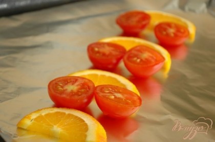 На лист фольги выложить дольки апельсина и половинки помидоров черри. На эту "подушку" поместить рыбу, маринад и сверху также положить несколько ломтиков апельсина.