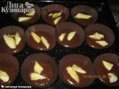 Выкладываем тесто для шоколадных кексов с бананами в бумажные  формочки и добавляем  нарезаный банан.