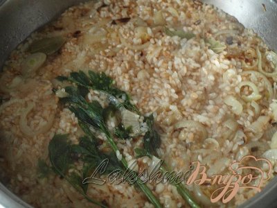 Когда рис станет коричневым — добавить бульон, веточки петрушки, лавровый лист и соль.Варим на медленном огне до испарения жидкости и готовности риса.