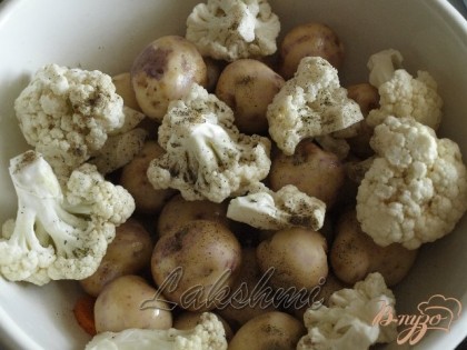 Цветную капусту разобрать на соцветия,добавить к картофелю.Добавить половину чеснока(зубками),посыпать перцем,добавить растительное масло,травы и хорошо перемешать.