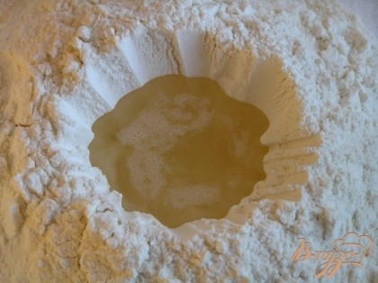 Приготовить тесто. Муку высыпать горкой на рабочую поверхность, слелать углубление и влить растопленное сало.