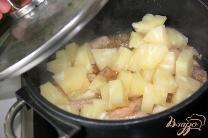 Добавить к мясу резаные ананасы, закрыть крышкой и тушить на среднем огне 8-10 минут.