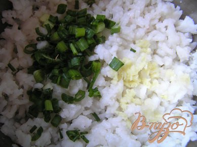 К рису добавить нарезанный лук и измельченный чеснок, перемешать.
