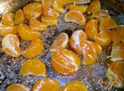 В это время приготовить начинку и глазурь. Разобрать мандарины на дольки, на сковороду налить 2 ст. л. воды и всыпать 2 ст. л. сахара, как только появятся пузырьки - всыпать мандариновые дольки, жарить, мешая, минут 5-в итоге получим карамельные дольки.