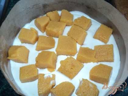 На корж вылить половину крема, выложить порезанное кубиками персиковое суфле,