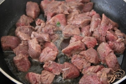 Шумовкой вытащить мясо из маринада и обсушить его в салфетках.  Обжарить мясо с двух сторон в течение 3 - 4 минут.Отдельно обжарить бекон до румяности и выложить его в горшочки.