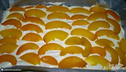 Выкладываем творожную массу на тесто.   Половинки консервированных персиков нарезаем на дольки и аккуратно выкладываем поверх равномерно как на пиццу.