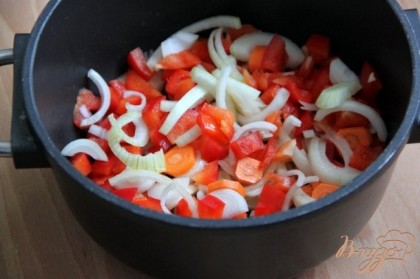 Лук нарезать полукольцами, морковь соломкой, перец кубиками и оставшийся чеснок измельчить. В глубоком сотейнике поджарить овощи на оливковом масле до прозрачности. Влить вино, дать покипеть 3-4 минуты на большом огне. Добавить оставшиеся специи.Добавить помидоры из банки вместе с томатным соусом.
