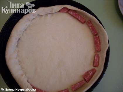 По краям разложите брусочки колбасы. Заверните и прищепните тесто, накрывая колбасу (туда же можно положить кусочки сыра).