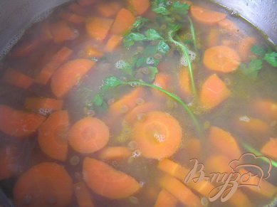 Чечевицу залить бульоном, довести до кипения, добавить морковь и варить около часа. В конце варки добавить несколько веточек кинзы.