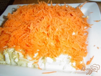 Морковь очищаем,натираем на мелкой терке и выкладываем на яичный слой,смазываем соусом - это четвертый слой.