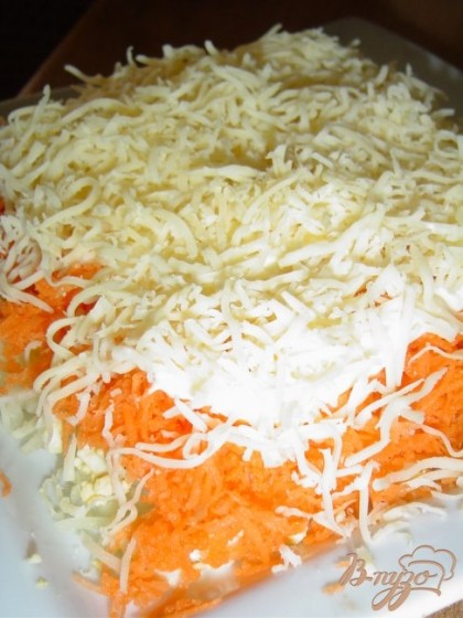 Пятым слоем будет сыр, который натираем на мелкой терке и выкладываем на морковь и опять смазываем соусом.