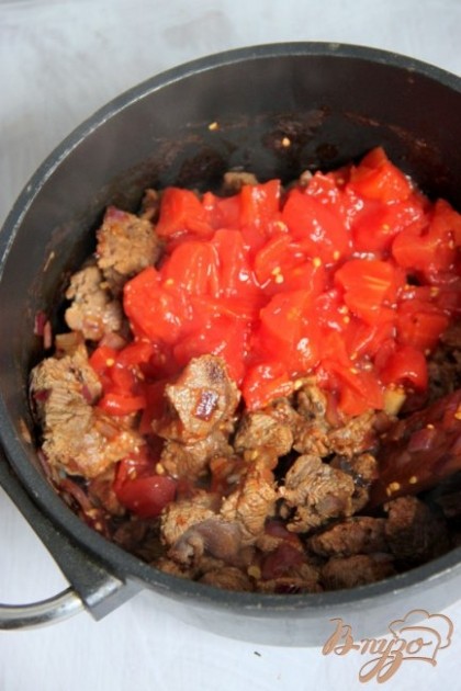 Добавить помидоры в соственном соку, немного, воду, посолить и продолжить варить, пока мясо не будет совсем готово.