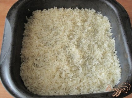 Хорошо промываем рис. Для этого блюда лучше использовать длинно зерновой рис. Разогреваем духовку до 200гр. На дно жаропрочной посуды выкладываем ровным слоем рис.