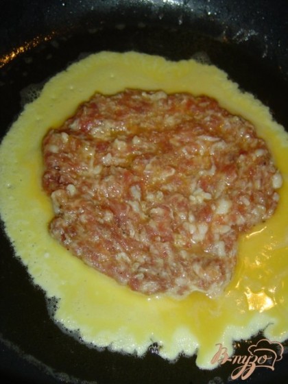 Разогреваем сковороду с небольшим кол-вом растительного масла, выливаем яйцо, а затем спускаем с тарелки в центр мясной блинчик, накрываем крышкой и обжариваем на среднем огне с двух сторон.