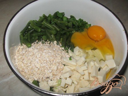 Зеленый лук мелко режем. Стручковую фасоль обдаем кипятком. Если она очень твердая, можно проварить минут пять.  Сыр режем кубиком. Разбиваем яйца. А также кладем овсянку и соль.