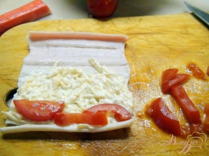На развёрнутую палочку намазываем тонким слоем сырную начинку, не доходя 2см. до края.Поверх сыра выкладываем брусочки помидор.Сворачиваем в рулетик.
