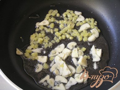 Отварить рис в подсоленой воде до готовности. Пока варится рис, в большой сковороде хорошо разогреть оливковое масло. Высыпать мелко нарезанные чеснок и имбирь. Жарить 1 минуту.