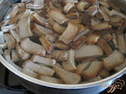 Ржаной хлеб нарезать и подсушить в духовке. В 3-х литровой кастрюле вскипятить воду с сухариками.  Дать остыть до комнатной температуры.