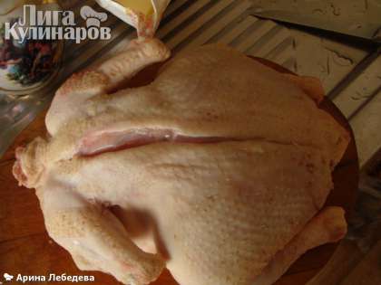 Выпотрошенную и промытую курицу положить на разделочную доску грудкой вниз. От шейки сделать продольный разрез.