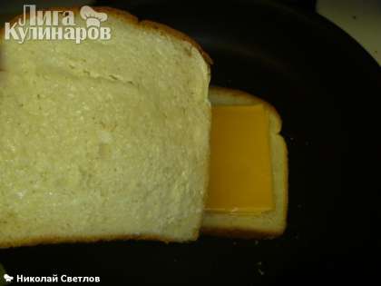 Мажем второй ломтик хлеба оставшейся половинкой масла и накрываем хлеб с сыром, причем ломтик кладем маслом верх.