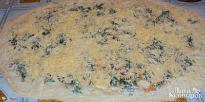 На рабочей поверхности разложить первый лист лаваша, посыпать тертым сыром и равномерно распределить сыр по всей поверхности лаваша.