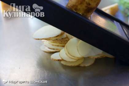 Тонко нарежьте картофель. Лучше всего использовать специальный слайсер.
