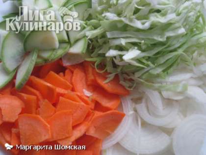 Капусту нашинковать, луковицу нарезать полукольцами, кабачок и морковь разрезать вдоль на 4 части и тоже нашинковать. Зубок чеснока очистить и раздавить ножом.