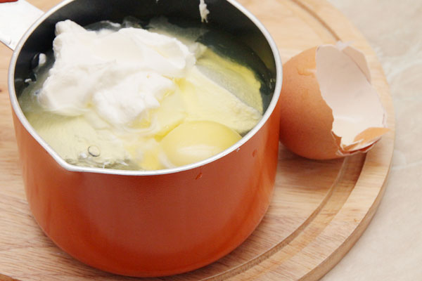 Поставьте на плиту молоко кипятиться, а тем временем в отдельной кастрюльке смешайте сметану с яйцами и солью.