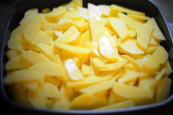 Очистить картофель, порезать тонкими пластинками.  Смазать емкость для запекания  оливковым маслом, разложить картофель, посолить.