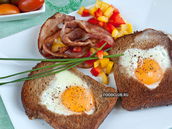 Подавайте яичницу в хлебе горячей, с поджаренным беконом и овощами.