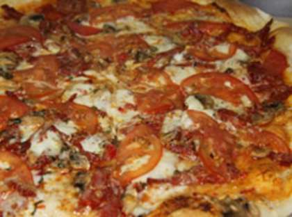 Готовую домашнюю пиццу вынуть из духовки, посыпать сухим базиликом сверху. Пицца должна немного остыть. Затем ее нужно нарезать на порционные кусочки и переложить их аккуратно на тарелки. Можем подавать к столу в таком виде.