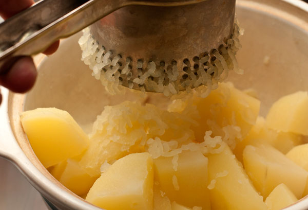 Слейте воду и быстро, пока картофель горячий, разомните ее толкушкой или пропустите через специальный пресс. 