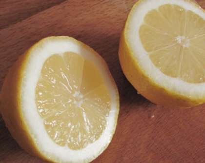 Промойте лимон и разрежьте на две части.