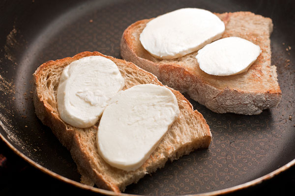Пока варится яйцо, подсушите свежий хлеб на сковороде без масла, затем переверните и положите на него ломтики моцареллы.