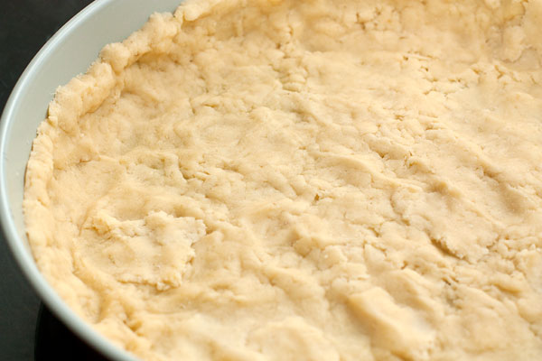 Охлажденное тесто раскатайте в тонкий пласт и выложите им форму для выпечки.   Сильно охлажденное тесто можно также натереть на терке или нарезать кусочками, которые распределить в форме.