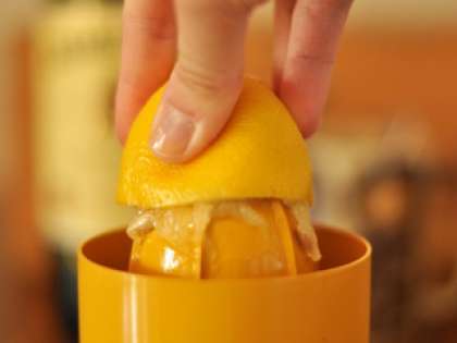 Промыть под проточной водой лимон. С помощью ножа на разделочной доске разрезать лимон пополам и выдавить сок с помощью соковыжималки.