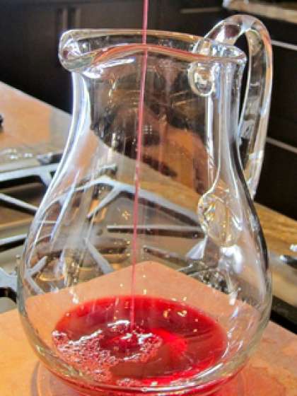 Влить красное сухое вино в глубокую миску.  Добавить  коньяк и воду. Все следует хорошо перемешать ложкой и оставить эту смесь настояться в течение 20 минут. После этого коктейль будет иметь насыщенный аромат и вкус.